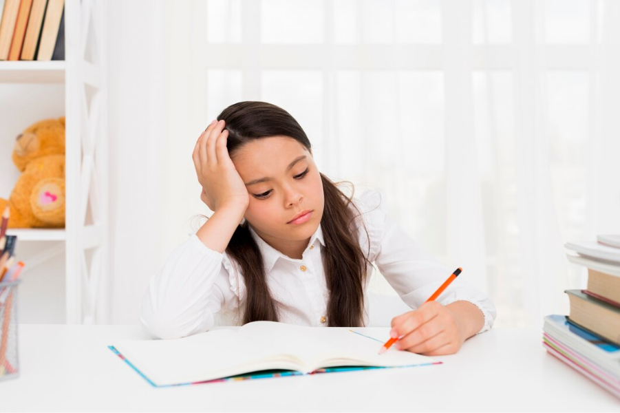 Girl Studying: Young girl looking frustrated while doing homework.